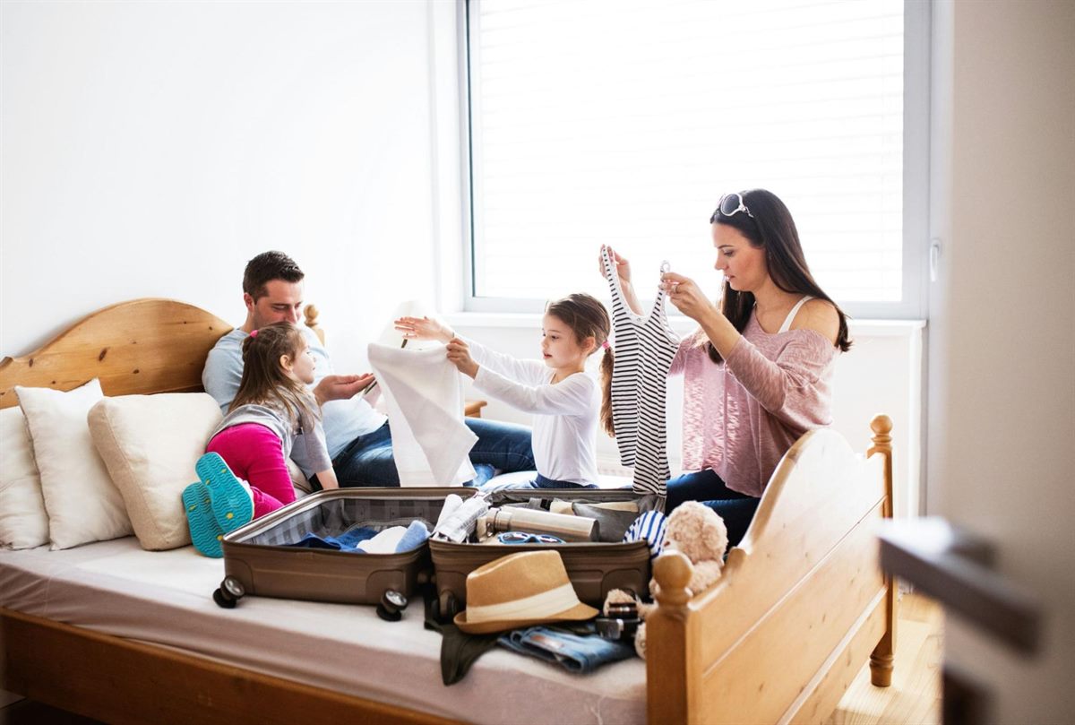 A family packing a suitcase together on a bed before a trip abroad